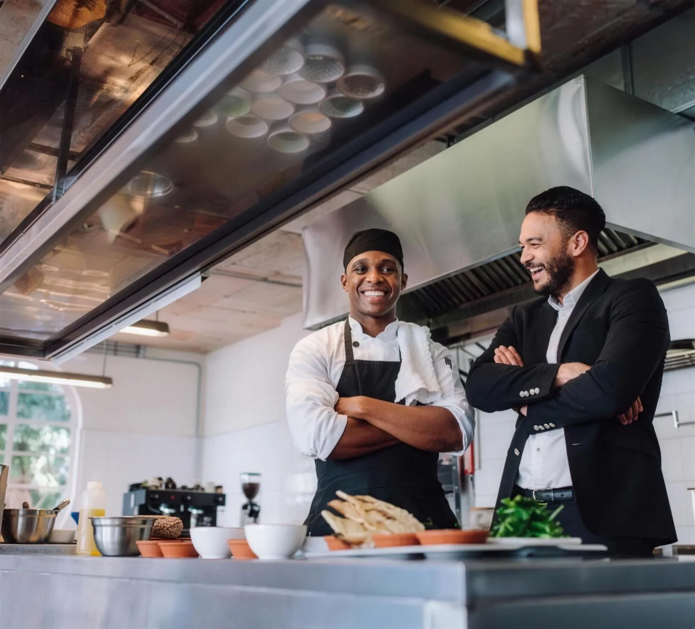 A chef and a restaurant manager talking in a working commercial kitchen
